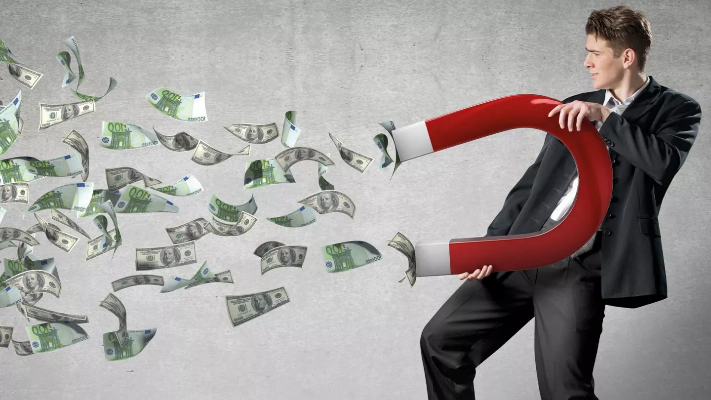 Mann zieht Geld mittels Magnet an Mann zieht Geld mittels Magnet an